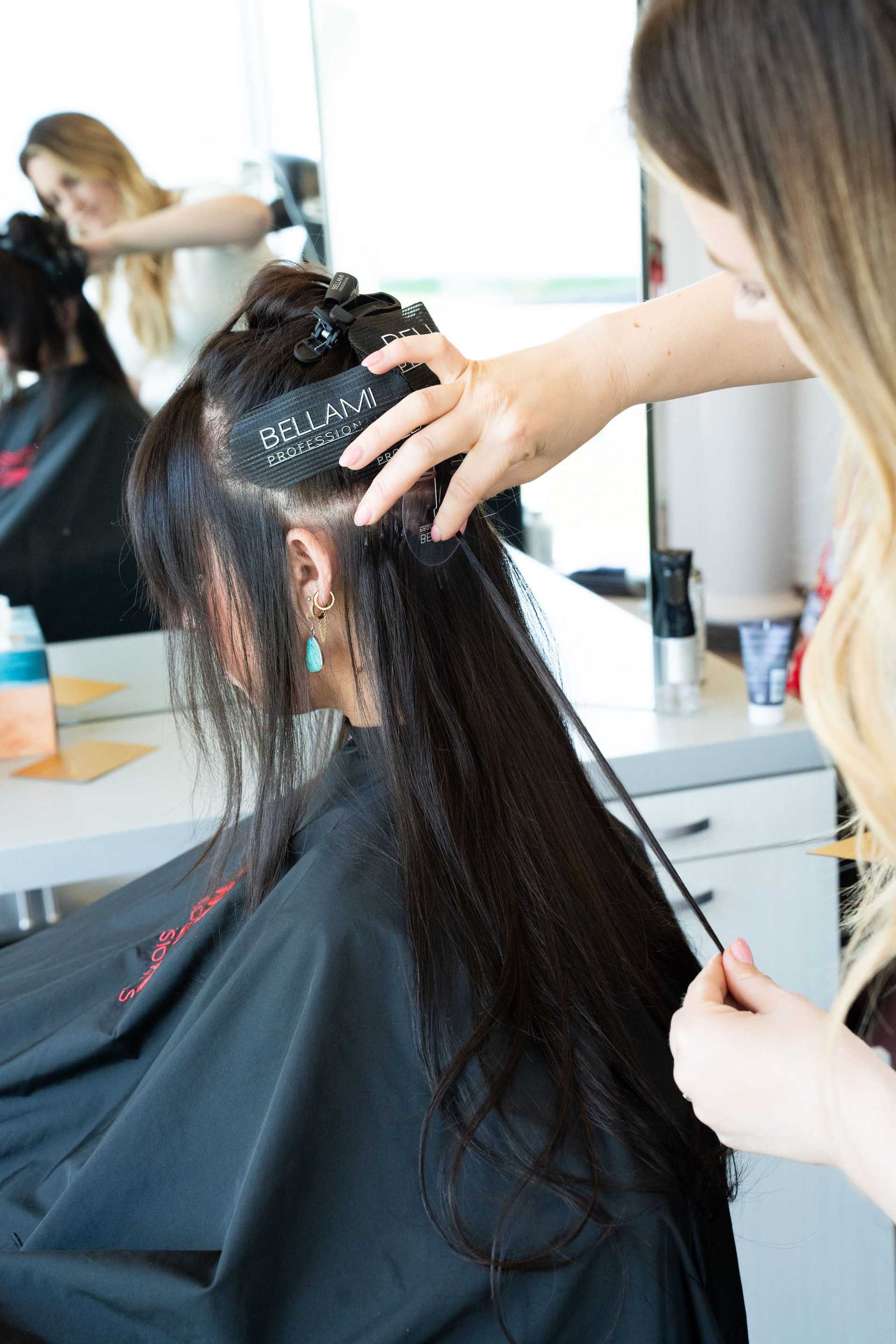 Hairdresser applying hair extensions in a salon setting.