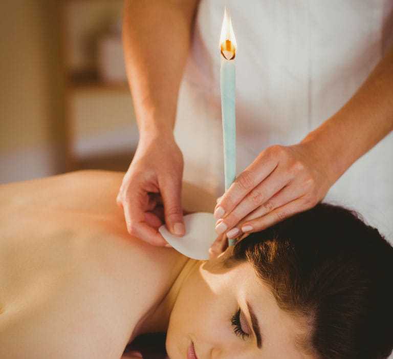 Ear candling therapy in progress on a woman lying down.