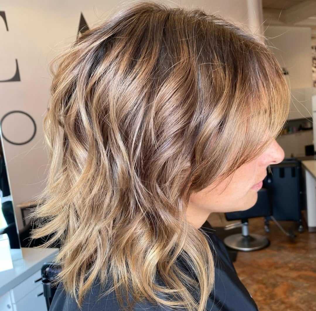 Wavy, layered hairstyle in a salon setting.