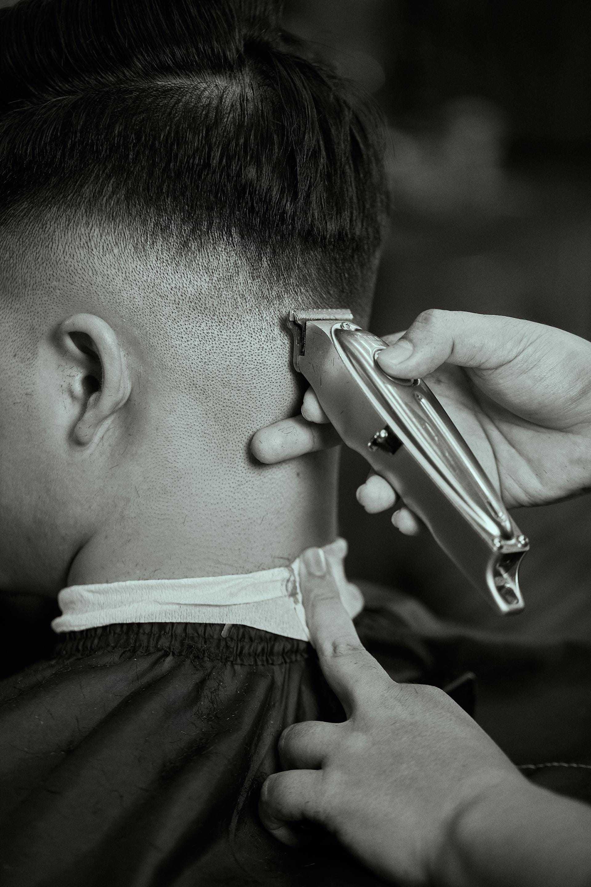Man getting a haircut with clippers and a neck tape.